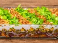 Warstwowa sałatka gyros w szklanym naczyniu, z kurczakiem, kukurydzą, ogórkiem, cebulą, serem, sosem i chrupiącą cebulką.