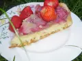 Pyszny biszkopt z truskawkami, udekorowany świeżymi owocami, czeka na letnią ucztę na talerzu z motywem kwiatowym.