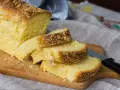 Puszyste ciasto drożdżowe bez wyrabiania, pokrojone na kromki, leży na desce. Kruszonka na wierzchu dodaje mu uroku.