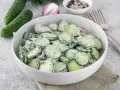 Mizeria z ogórków z koperkiem i czerwoną cebulą, polana kremowym sosem. Idealna śmietana do mizerii to taka, która podkreśli jej świeżość.