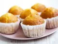 Idealny przepis na wilgotne i puszyste muffinki. Złociste, pachnące babeczki na różowym talerzyku.
