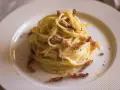 Pyszna carbonara bez śmietany, z chrupiącym boczkiem i czarnym pieprzem, podana na białym talerzu.