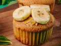 Pyszne muffinki bananowe z kremem orzechowym i plasterkami banana na drewnianej desce.