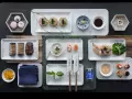 Elegancka aranżacja stołu z różnorodnymi przekąskami, w tym mini naleśnikami z kawiorem, sushi, krewetkami w tempurze i makaronikami. Idealne na wieczór, gdy masz ochotę na coś pysznego do sushi.