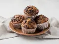 Cztery czekoladowe muffinki w papierowych foremkach, idealne do pieczenia.