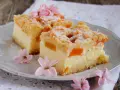 Pyszny sernik z brzoskwiniami, posypany cukrem pudrem i udekorowany delikatnymi kwiatami. Idealny na letnie popołudnie.