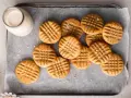 Stos ciastek z masłem orzechowym, posypanych solą, obok butelki mleka. Idealne na deser!