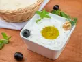 Pyszny sos tzatziki z oliwą, orzechami i miętą, podany z pitą w koszyku.