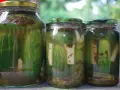 Słoiki z ogórkami kiszonymi, pełne aromatycznych przypraw i świeżych ziół.