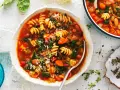 Minestrone co to? Aromatyczna zupa z makaronem, fasolą, warzywami i ziołami, podana w białej misce.