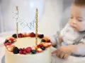 Uroczy tort na roczek dla chłopca, ozdobiony świeżymi owocami i chorągiewkami.