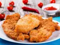 Chrupiące kotlety z kurczaka na talerzu, obok pomidorki i ketchupu. Idealne, gdy zastanawiasz się, ile smażyć kurczaka.