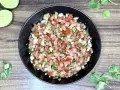 Świeże, posiekane pomidory, cebula, kolendra i papryczka jalapeno tworzą apetyczne pico de gallo w czarnej misce.
