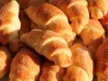 Złociste rogaliki drożdżowe posypane cukrem, niektóre z delikatnym nadzieniem. Idealne na śniadanie.