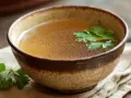Aromaticzny bulion w glinianej misce, ozdobiony natką pietruszki. Idealny przepis na to, jak zrobić bulion, który rozgrzeje serce.