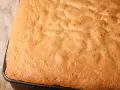 Puszysty biszkopt na tort, lekko zarumieniony, z widoczną strukturą pęcherzyków powietrza. Idealna baza do słodkich wypieków.