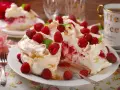 Pyszny tort bezowy z malinami, udekorowany listkami mięty. Idealny deser na letnie popołudnie.