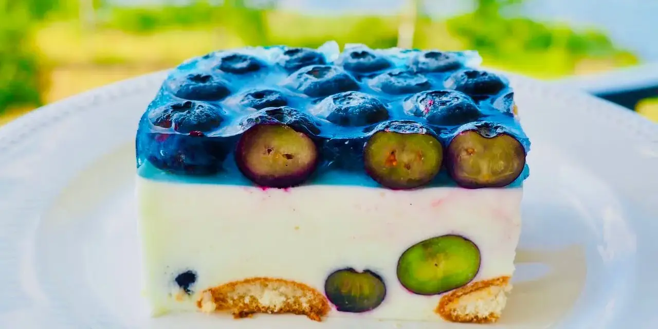 Sernik na zimno z borówkami, z warstwą kremu i galaretki, ozdobiony świeżymi owocami. Idealny na letnie popołudnie.