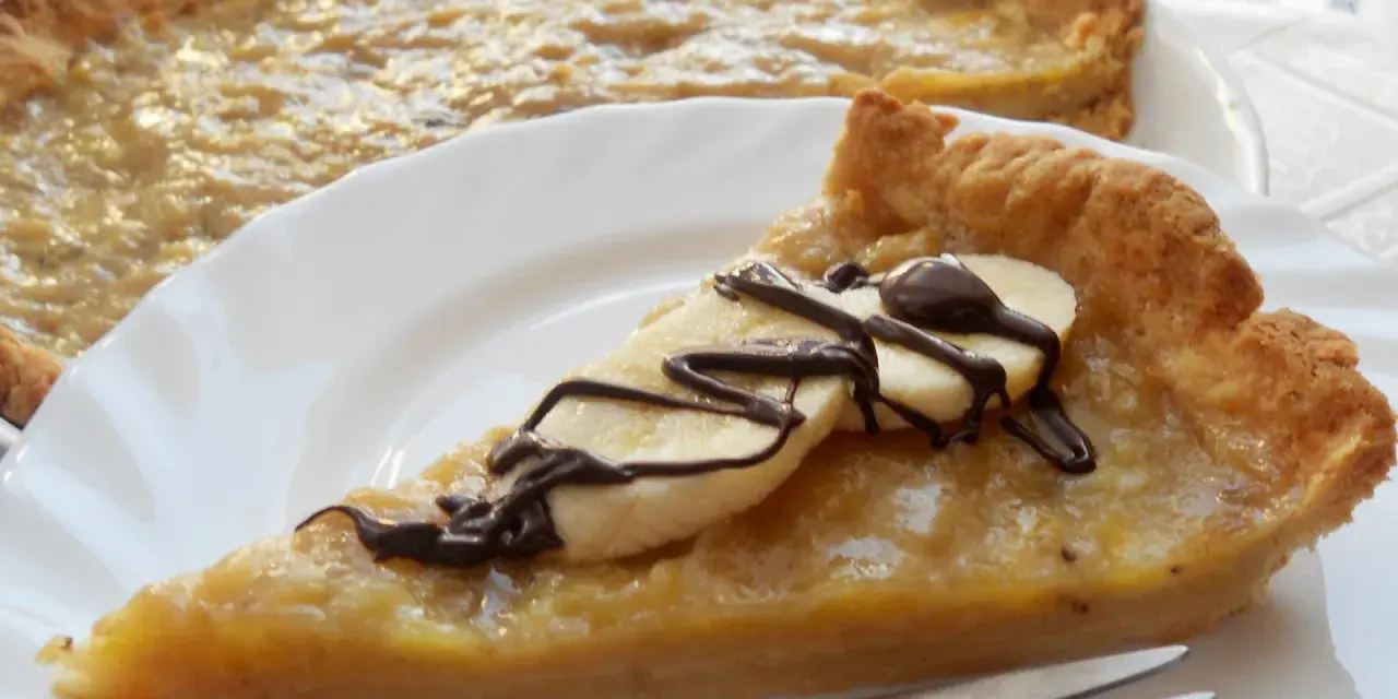 Pyszna tarta z bananami, udekorowana czekoladą i plasterkami banana, czeka na talerzu.