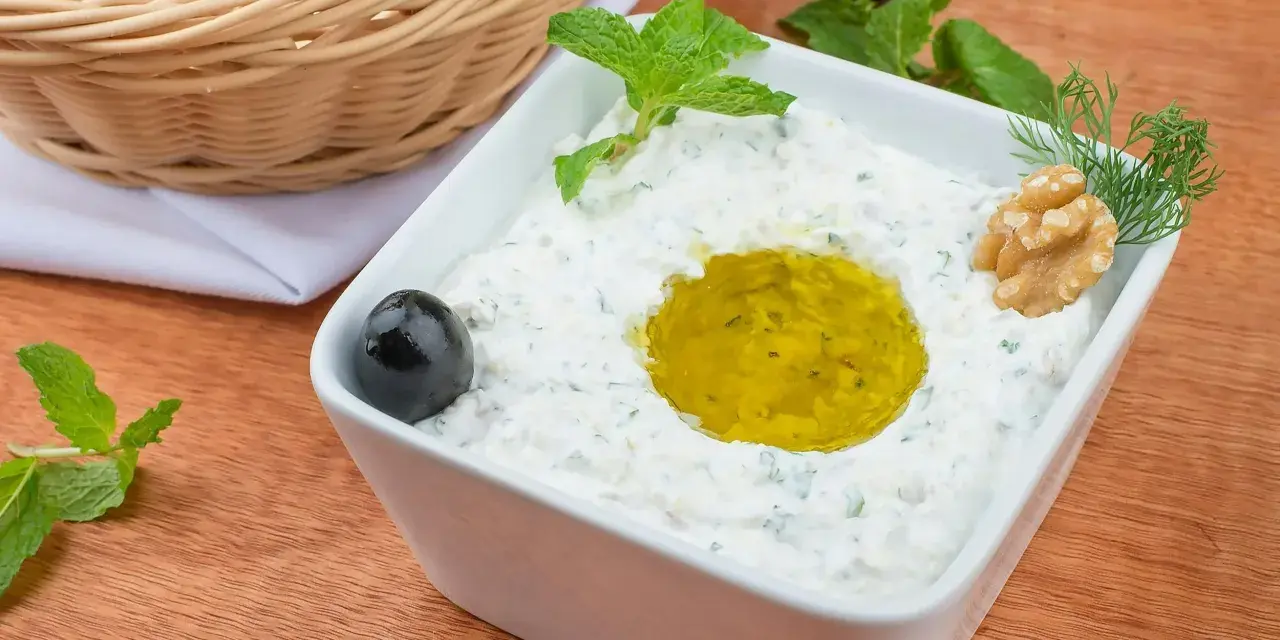 Pyszny sos tzatziki z oliwą, orzechami i miętą, podany z pitą w koszyku.