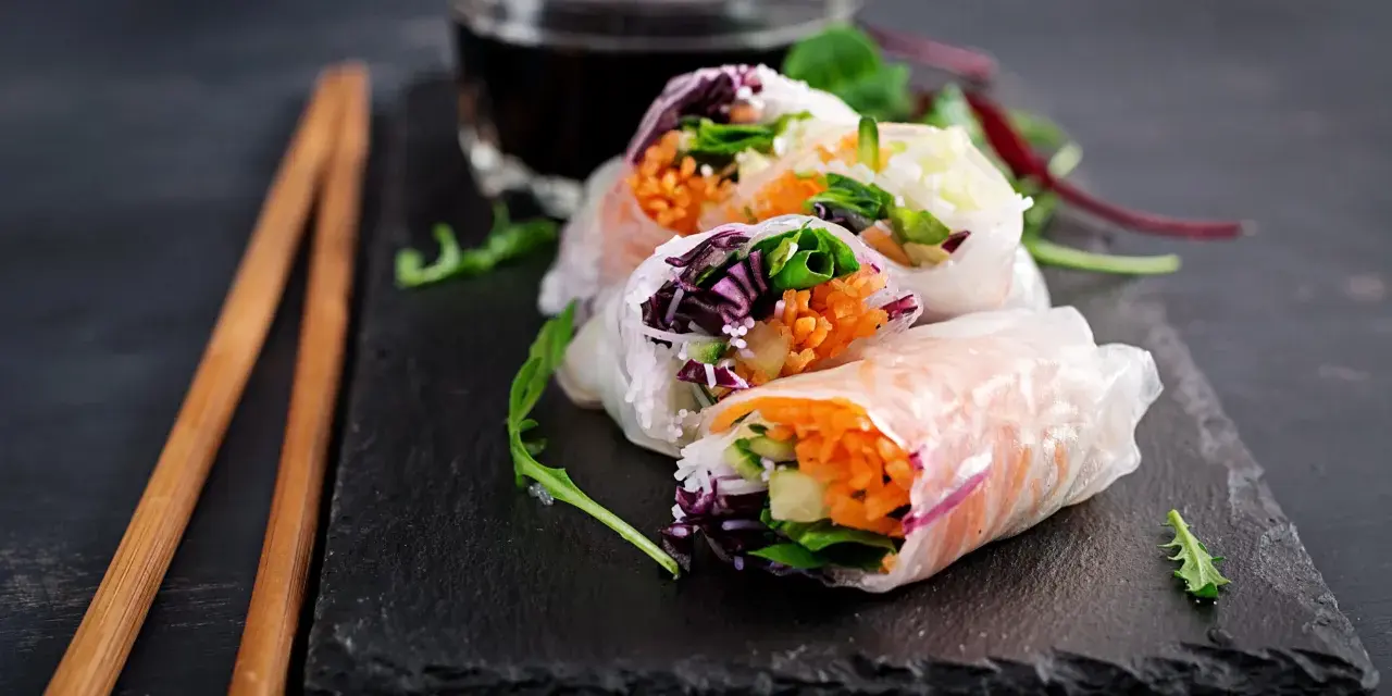 Świeże spring rolls z warzywami i łososiem, podane z sosem.