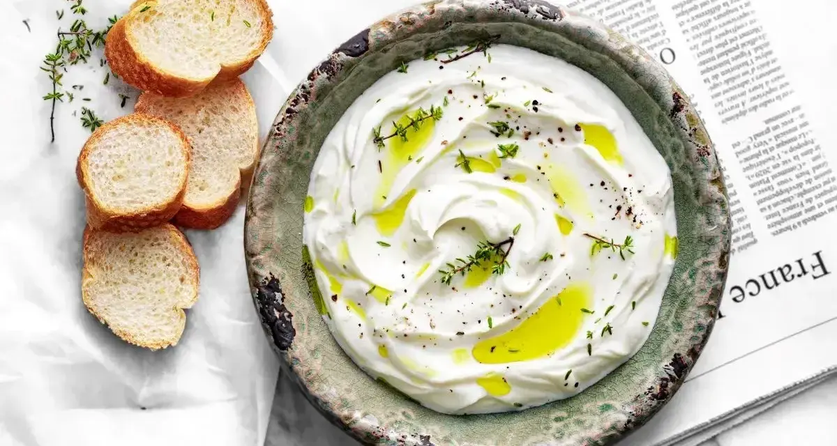 Labneh co to? Kremowy serek jogurtowy, polany oliwą, z ziołami i pieprzem, podany z kromkami bagietki.