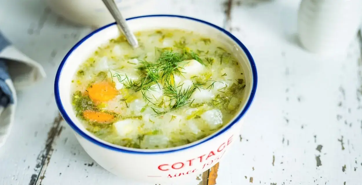 Aromaticzna zupa koperkowa z ziemniakami i marchewką, udekorowana świeżym koperkiem, podana w miseczce z napisem "Cottage".