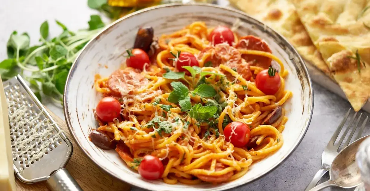 Pyszne spaghetti z chorizo, pomidorkami koktajlowymi i świeżą bazylią, posypane parmezanem. Idealne danie dla miłośników włoskich smaków.