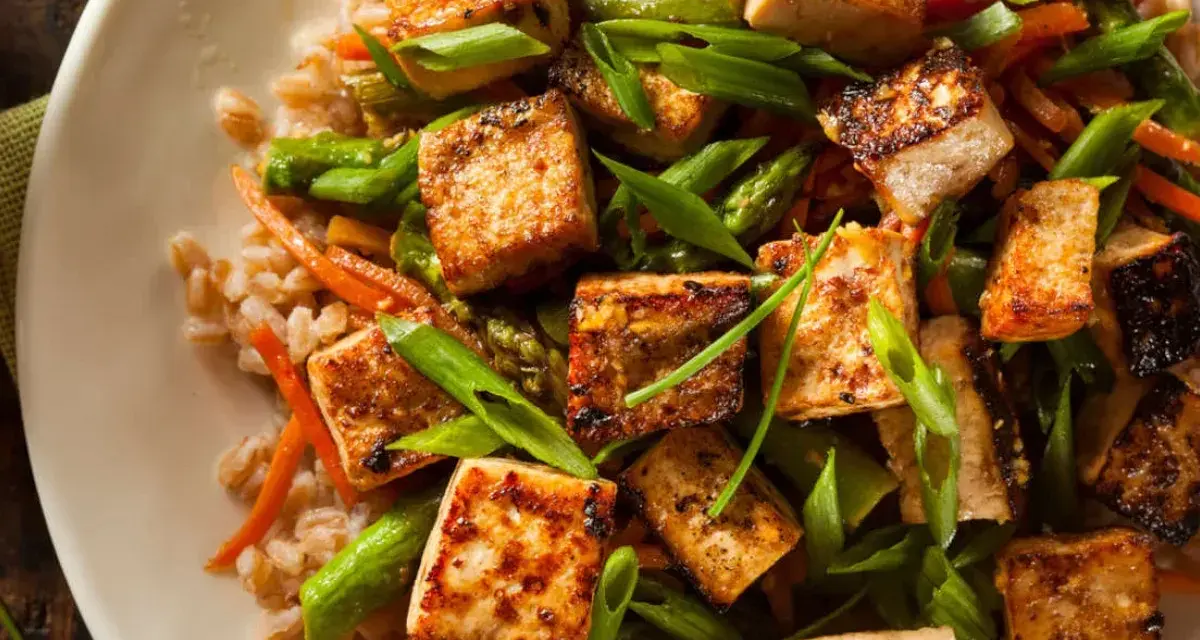 Pyszne tofu na obiad z ryżem, szparagami i marchewką. Danie wygląda apetycznie i zdrowo.