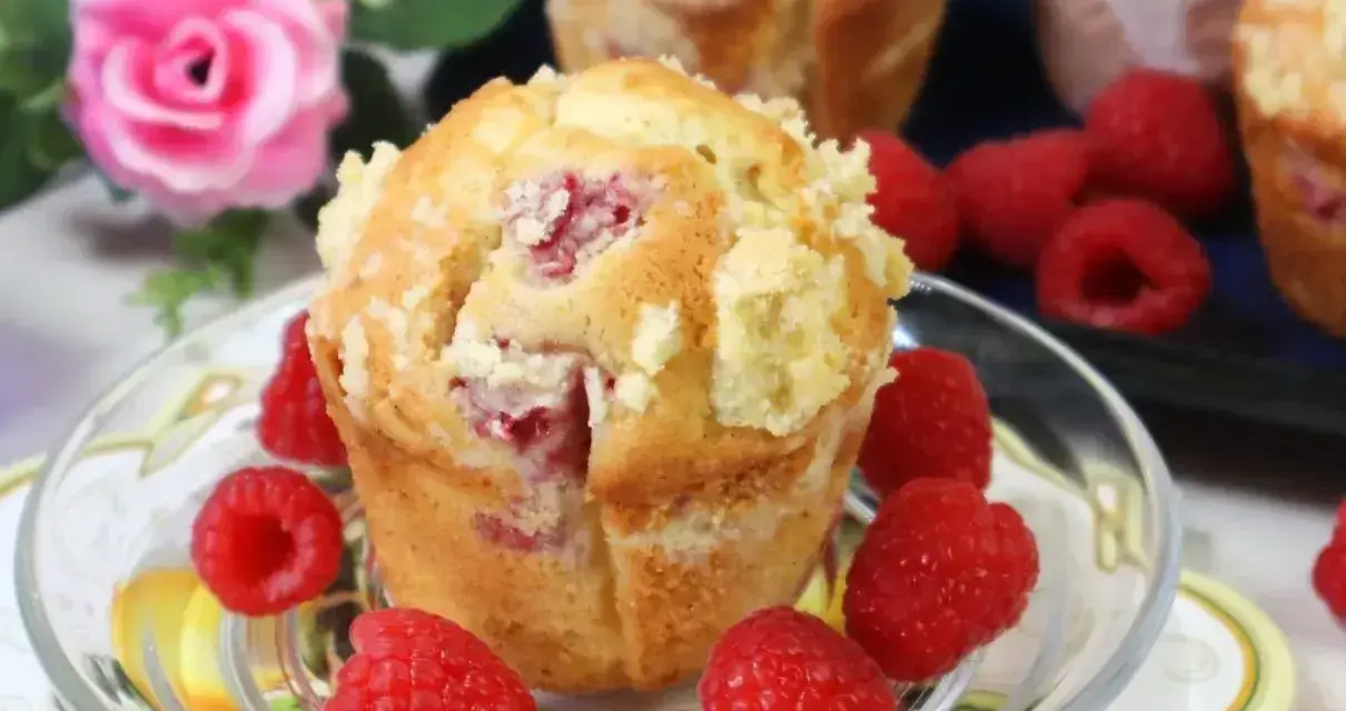 Pyszne muffinki z malinami, posypane kruszonką, otoczone świeżymi malinami. Idealne na deser.