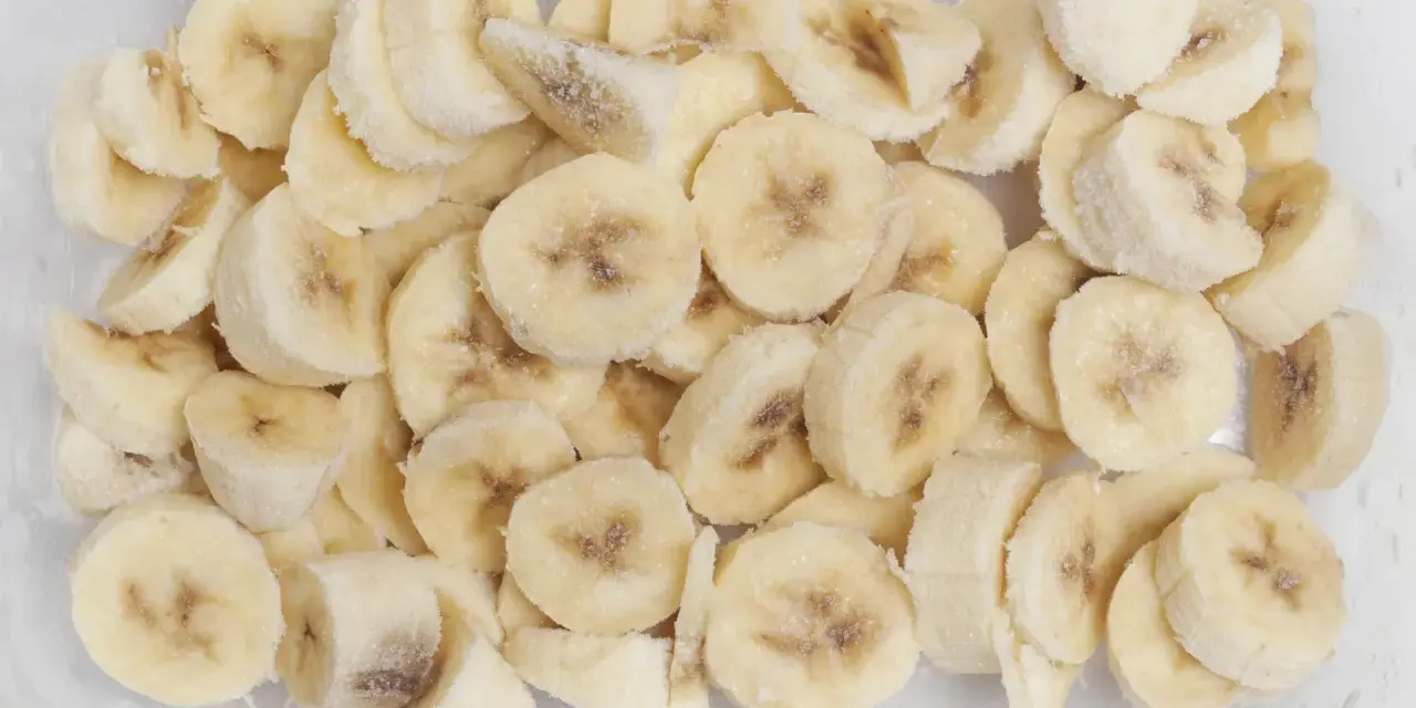 Pokrojone w plasterki banany w pojemniku, pokryte szronem. Tak, banany można mrozić, idealne do smoothie!
