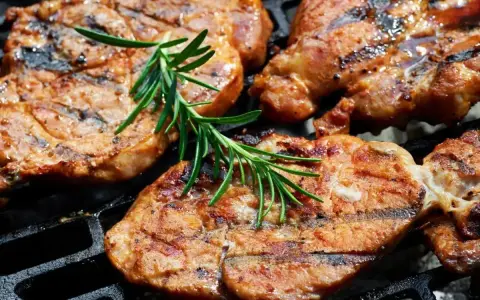 Soczysta karkówka na grillu, idealnie przyprawiona, z gałązką rozmarynu. Doskonały pomysł na to, jak przyprawić karkówkę na grilla.