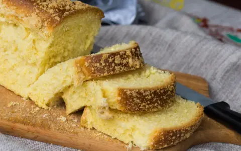 Puszyste ciasto drożdżowe bez wyrabiania, pokrojone na kromki, leży na desce. Kruszonka na wierzchu dodaje mu uroku.