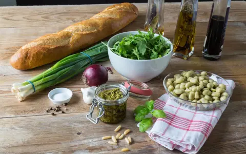 Składniki na pyszne pesto z bobu: świeży bób, bazylia, orzeszki piniowe, czosnek, oliwa, bagietka i rukola.