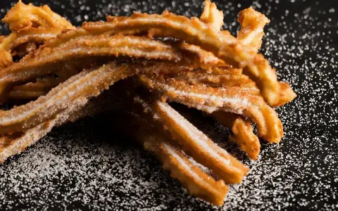 Złociste churros posypane cukrem, idealne na słodką przekąskę. Prosty churros przepis dla każdego.