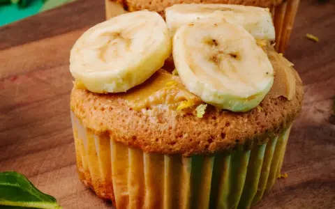 Pyszne muffinki bananowe z kremem orzechowym i plasterkami banana na drewnianej desce.