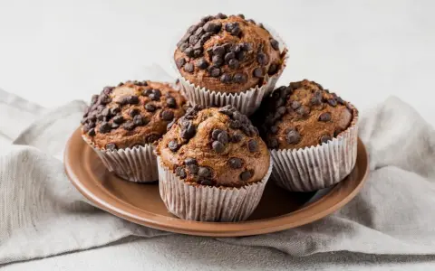 Cztery czekoladowe muffinki w papierowych foremkach, idealne do pieczenia.