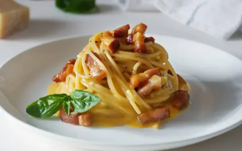 Pyszna carbonara z chrupiącym boczkiem i bazylią. Jaki ser do carbonary? Najlepszy jest parmezan lub pecorino romano.