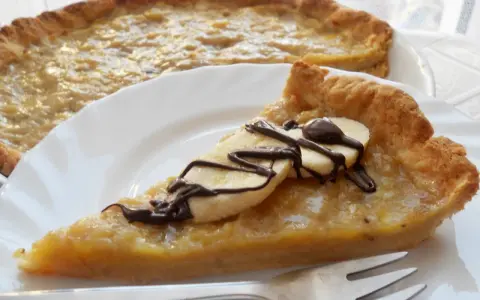 Pyszna tarta z bananami, udekorowana czekoladą i plasterkami banana, czeka na talerzu.