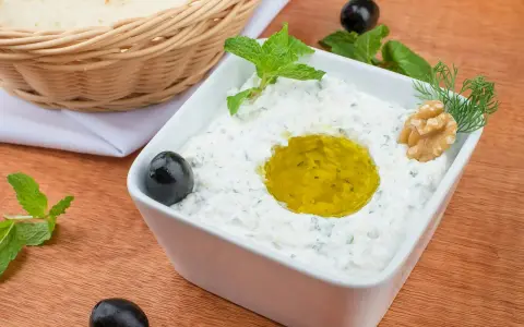 Pyszny sos tzatziki z oliwą, orzechami i miętą, podany z pitą w koszyku.