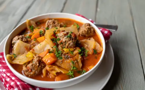 Aromaticzna zupa gołąbkowa z klopsikami, kapustą i marchewką, posypana natką pietruszki.