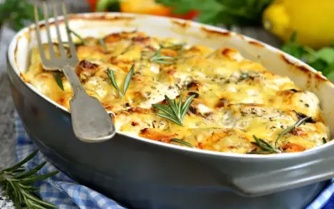 Pyszna zapiekanka makaronowa z serem i ziołami, podana w naczyniu, gotowa do podania.