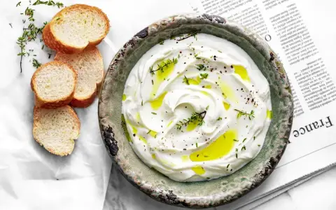 Labneh co to? Kremowy serek jogurtowy, polany oliwą, z ziołami i pieprzem, podany z kromkami bagietki.
