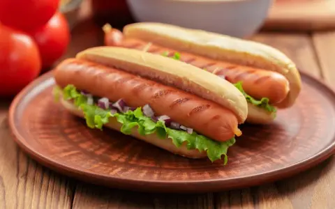 Dwa apetyczne hot dogi z grillowanymi parówkami, sałatą i cebulką. Zastanawiasz się, czy można mrozić parówki? Tak, można je mrozić!