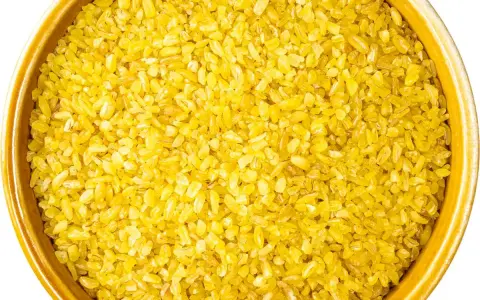 Żółta kasza bulgur w ceramicznej misce, gotowa do gotowania. Idealna baza do zdrowych dań.