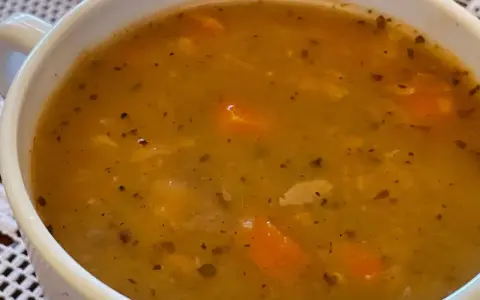 Gęsta, aromatyczna zupa grochowa z kawałkami marchewki i przyprawami, podana w białej miseczce.