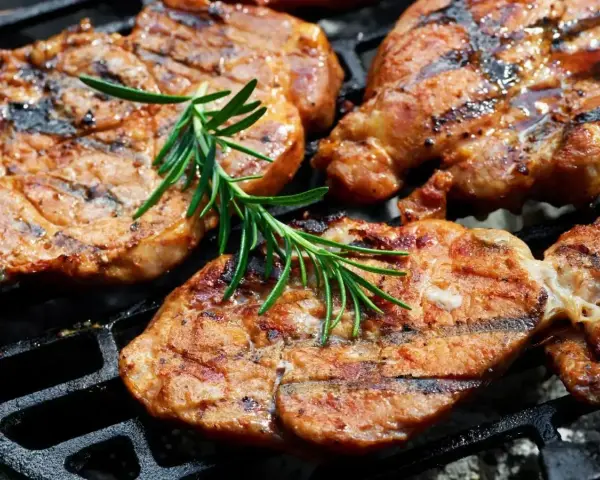 Soczysta karkówka na grillu, idealnie przyprawiona, z gałązką rozmarynu. Doskonały pomysł na to, jak przyprawić karkówkę na grilla.