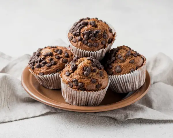 Cztery czekoladowe muffinki w papierowych foremkach, idealne do pieczenia.