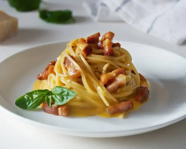 Pyszna carbonara z chrupiącym boczkiem i bazylią. Jaki ser do carbonary? Najlepszy jest parmezan lub pecorino romano.