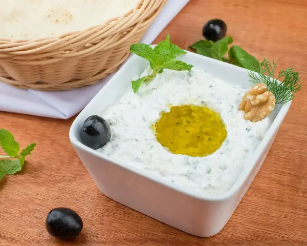 Pyszny sos tzatziki z oliwą, orzechami i miętą, podany z pitą w koszyku.